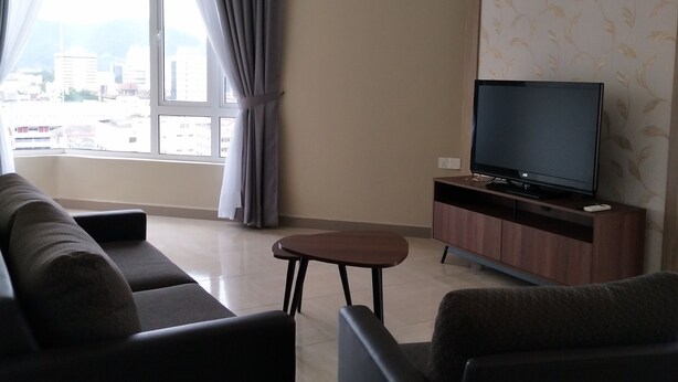 A living room with a sofa, a coffee table, and a TV on a wooden stand. - The Octagon Ipoh (Ipoh)
