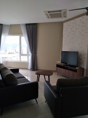 A living room with a sofa, a coffee table, and a TV on a wooden stand. - The Octagon Ipoh (Ipoh)