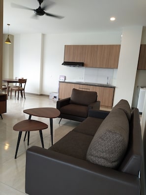 Una sala moderna con un sofá, dos mesitas y un comedor con sillas.