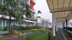 A modern building with a covered walkway, green artificial grass, and various plants. - The Octagon Ipoh (Ipoh)