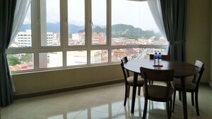 A room with a large window, a dining table with chairs, and a bottle on the table. - The Octagon Ipoh (Ipoh)