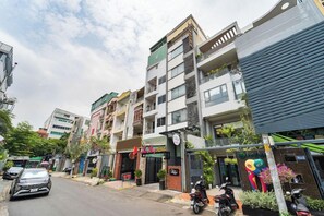 A multi-story hotel with balconies, a sign for a restaurant, and parked scooters.