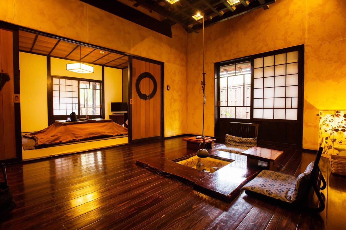 A traditional Japanese room with tatami flooring, a low table, a cushioned bench, and sliding doors.