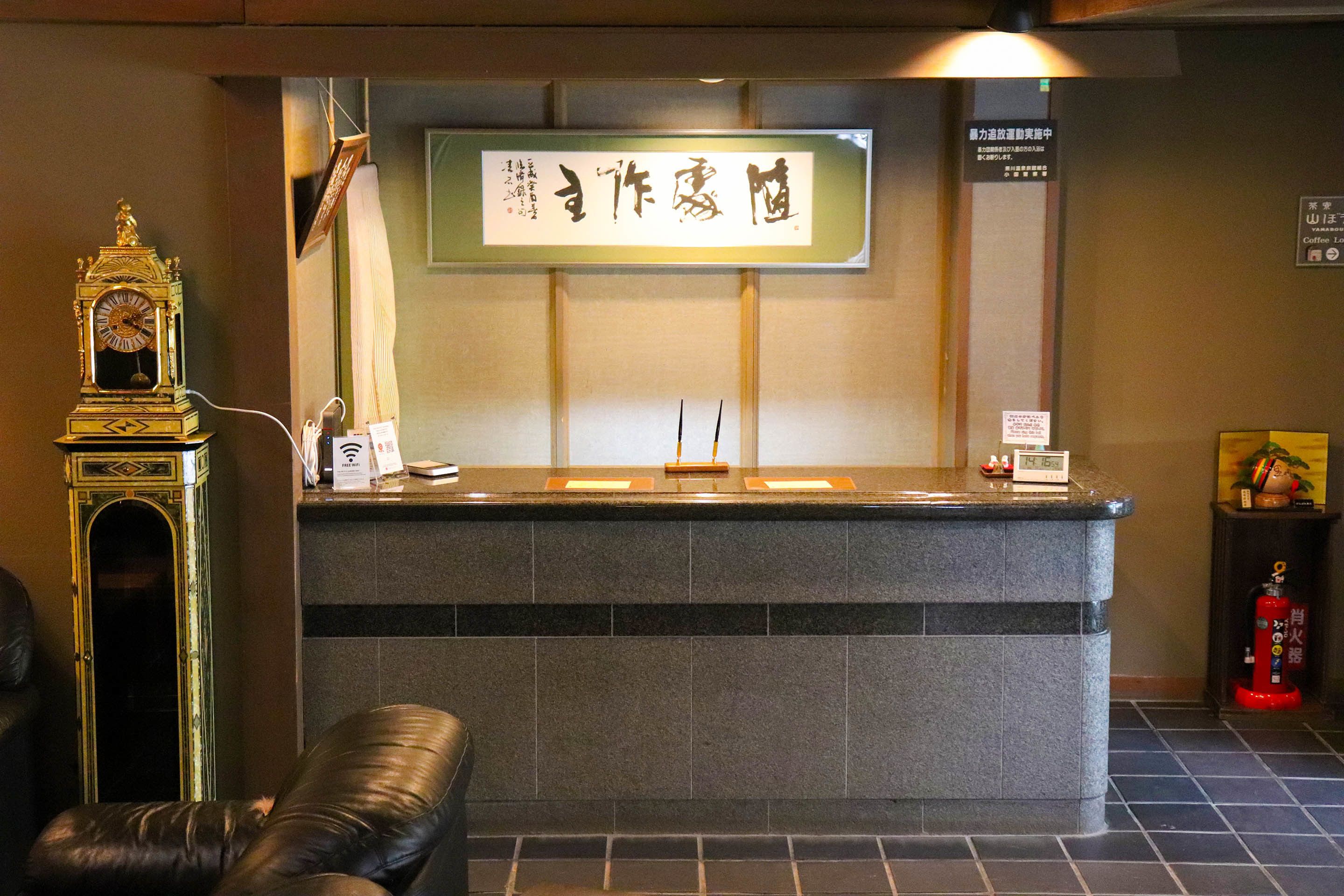 A reception desk with a traditional clock, a sign with Japanese characters, and a fire extinguisher.
