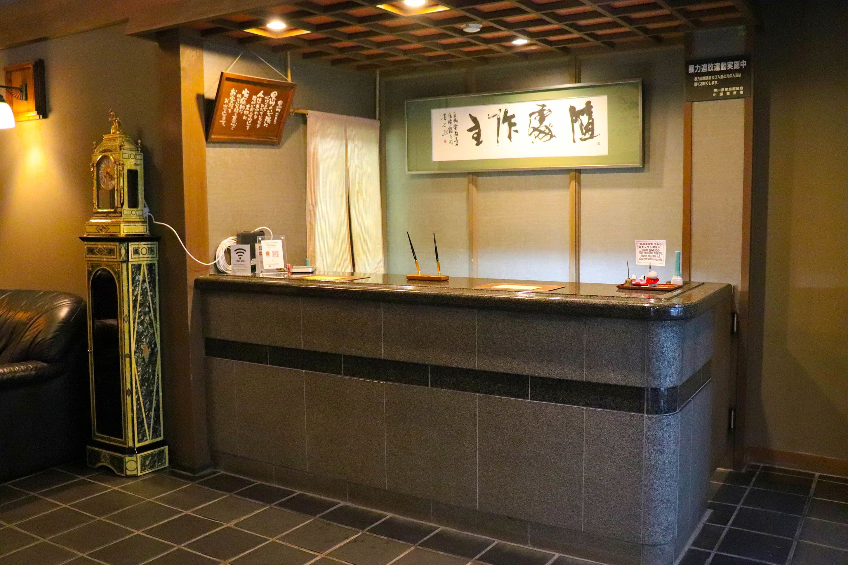 A reception desk with a clock, a framed calligraphy piece, and a sign with Japanese characters.