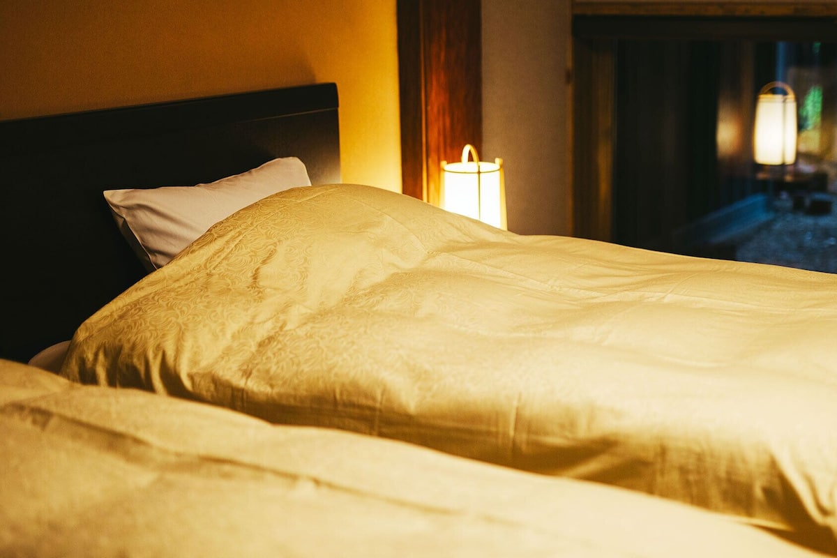 A bed with a headboard and a bedside lamp in a hotel room.
