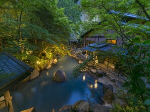 A serene riverside setting with traditional architecture, a clear path, and a tranquil water feature. - Kurokawaso (Minamioguni)