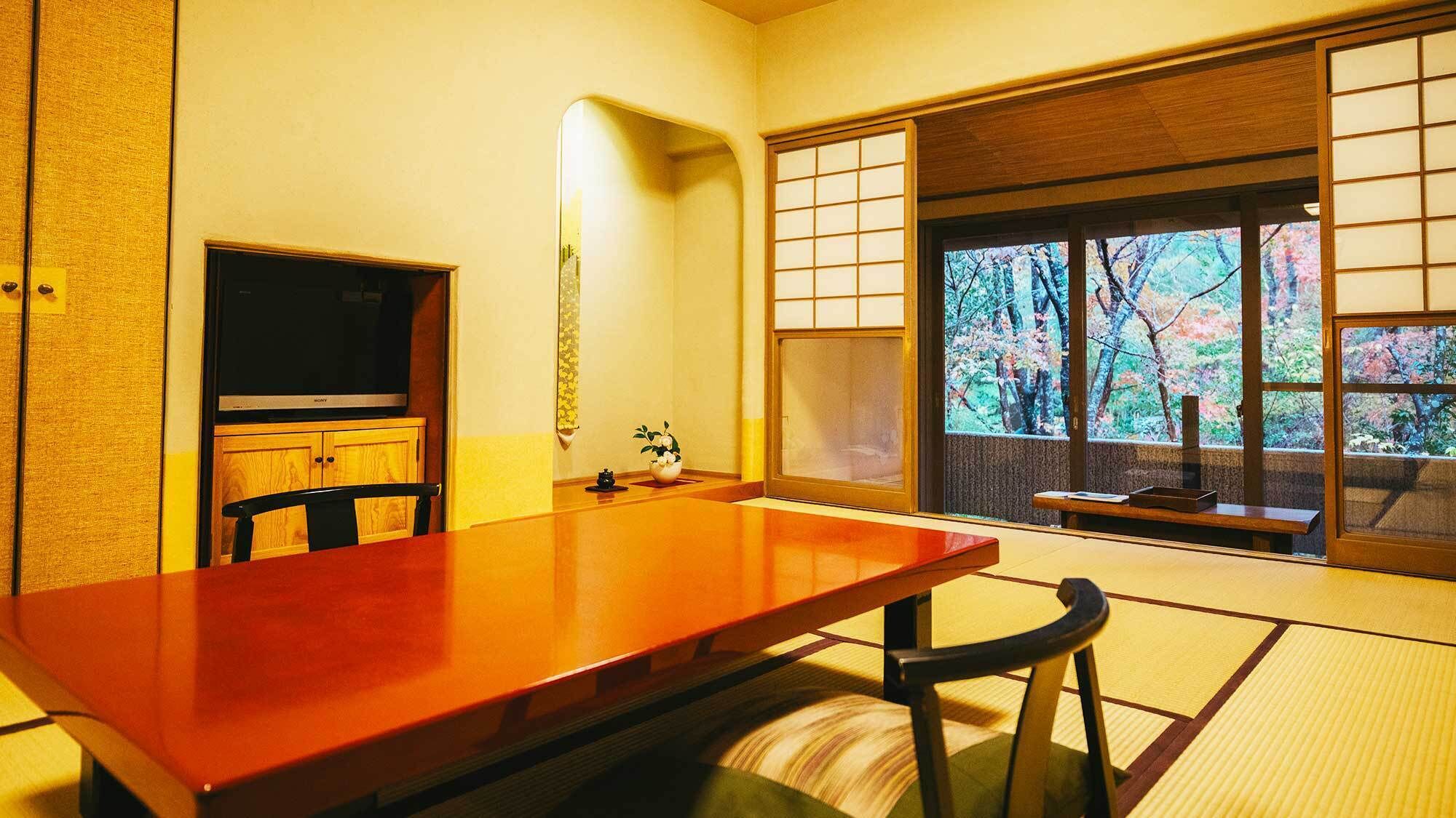 A traditional Japanese room with tatami flooring, a wooden table, a television, and a view of trees through a shoji screen.
