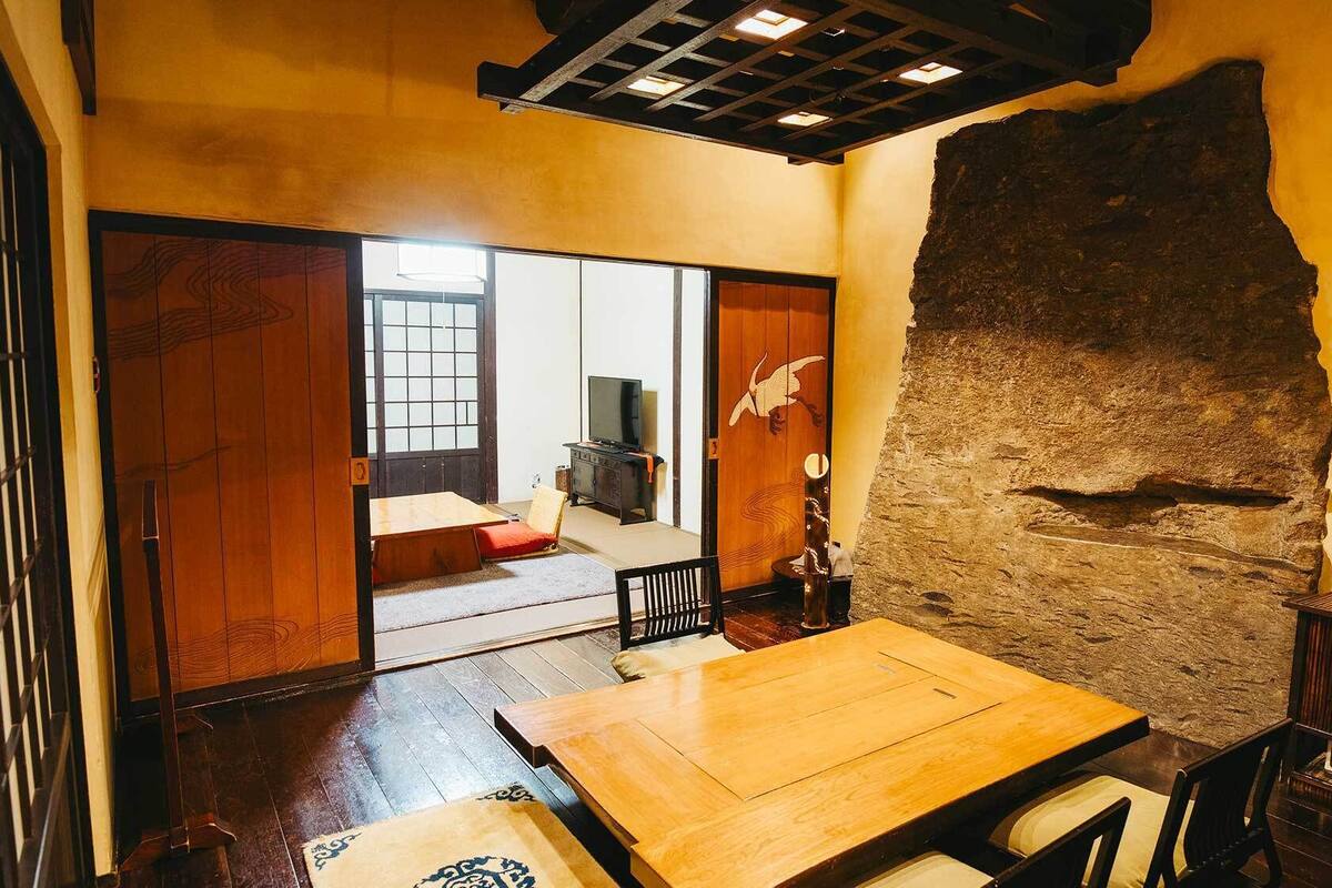 A traditional Japanese room with tatami flooring, a low wooden table, sliding doors, and a stone wall.