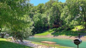 Un área de picnic con una mesa, bancos, una parrilla y un río.
