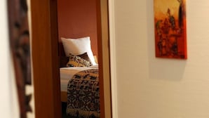 Een hotelkamer met een bed, een deur en een schilderij aan de muur.