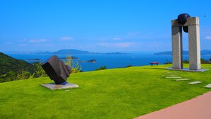 Una escultura en una colina cubierta de hierba con vistas al mar y a islas distantes.