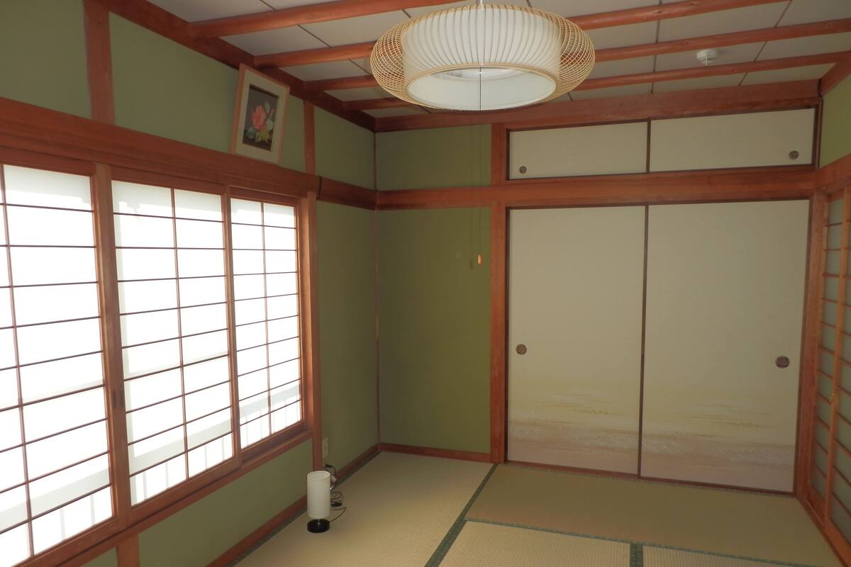 Una habitación japonesa tradicional con suelo de tatami, puertas correderas y una lámpara colgante.