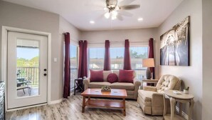 A living room with a sofa, armchair, coffee table, and a ceiling fan.