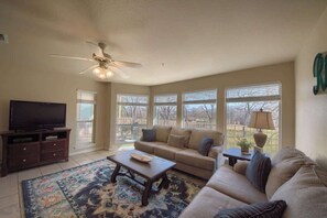 A living room with a sofa, coffee table, TV, and a ceiling fan.