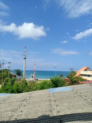 A coastal view with a lighthouse, a beach, and a building with a red roof.