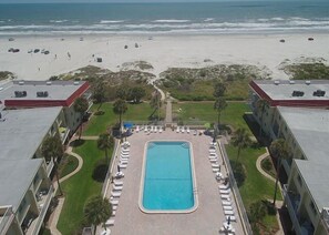 A hotel with a swimming pool surrounded by lounge chairs, a beach view, and a parking area. - Spanish Trace 240: Secure Gated Beachfront Condo with Pool, Sleeps 6 (Saint Augustine)