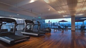 A modern gym with treadmills, elliptical machines, and free weights. It features large windows with a city view. - Greystone Haus at D' Majestic Place (Kuala Lumpur)