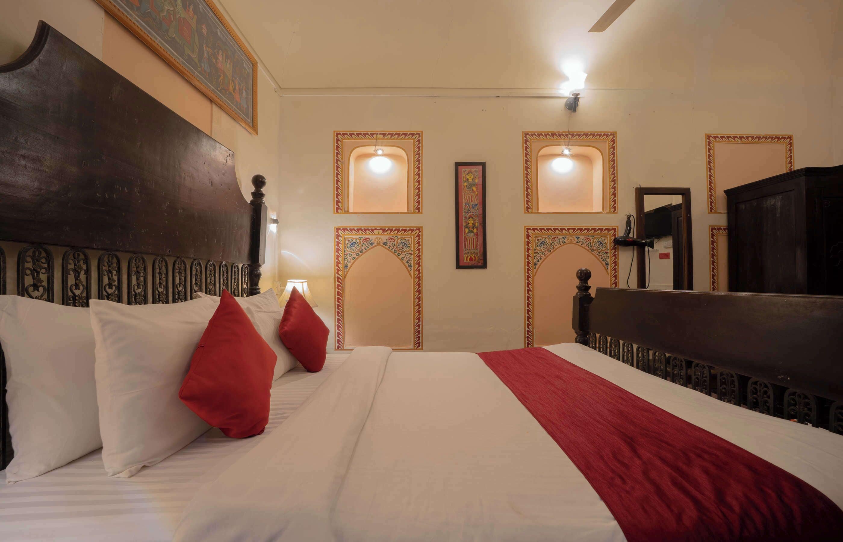 Habitació d'hotel amb un llit gran, un capçal de fusta i panells decoratius a la paret.