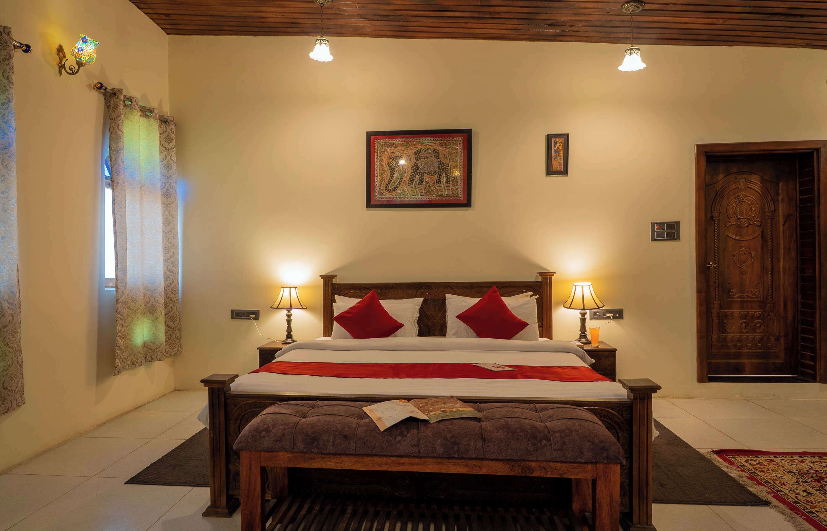 A neatly arranged bedroom with a wooden bed, two bedside lamps, a framed picture on the wall, and a wooden door.