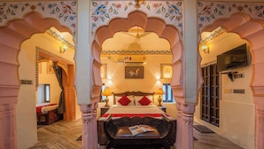 Ein traditionell eingerichtetes Zimmer mit Bett, Sitzbank und Fernseher.