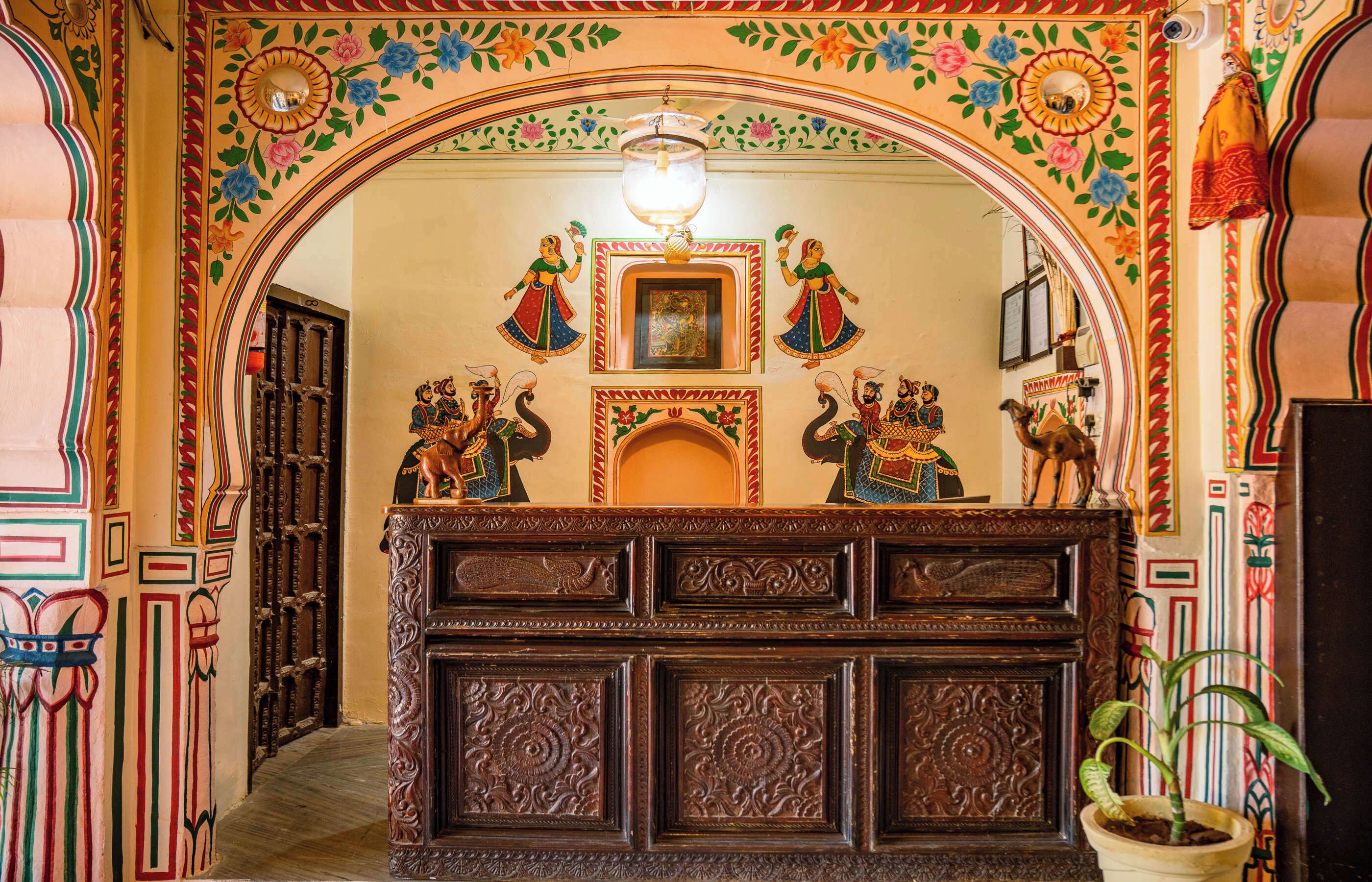 An ornate reception desk with intricate carvings and a mirror above it.
