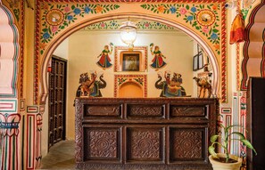 Uma receção ornamentada com esculturas detalhadas e um espelho em cima.