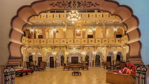 Ein prächtiger Saal mit aufwendiger Architektur, einem Chandelier und Sitzgelegenheiten.