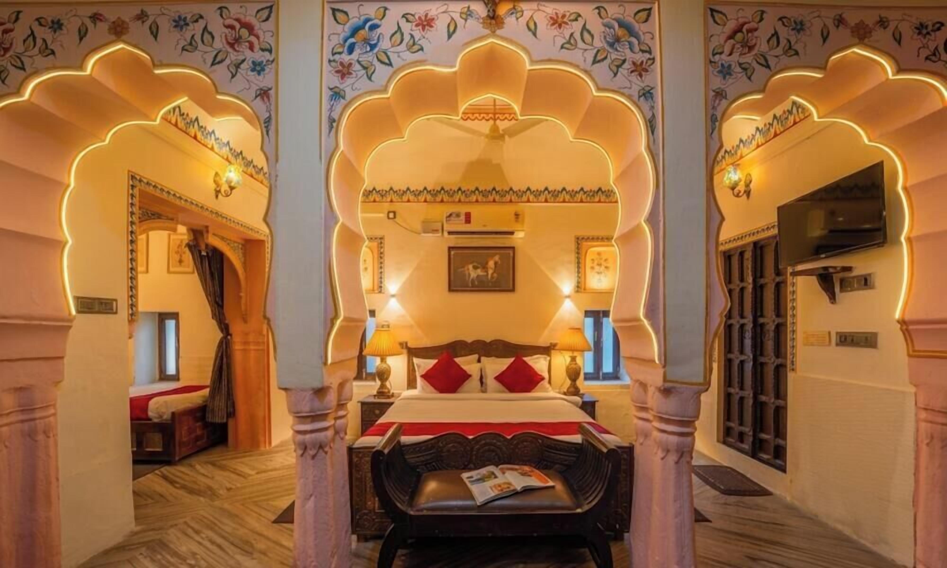 A traditional room with a bed, a television, and decorative arches.