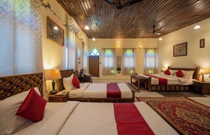 Quarto de hotel com duas camas, teto de madeira e um tapete grande.