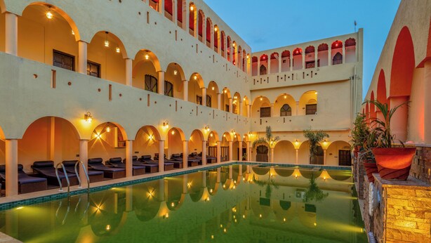 Ein Hotel mit großem Innenpool, mehreren Balkonen und warmer Beleuchtung.