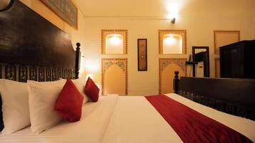 A hotel room with a large bed, a wooden headboard, and decorative wall sconces.