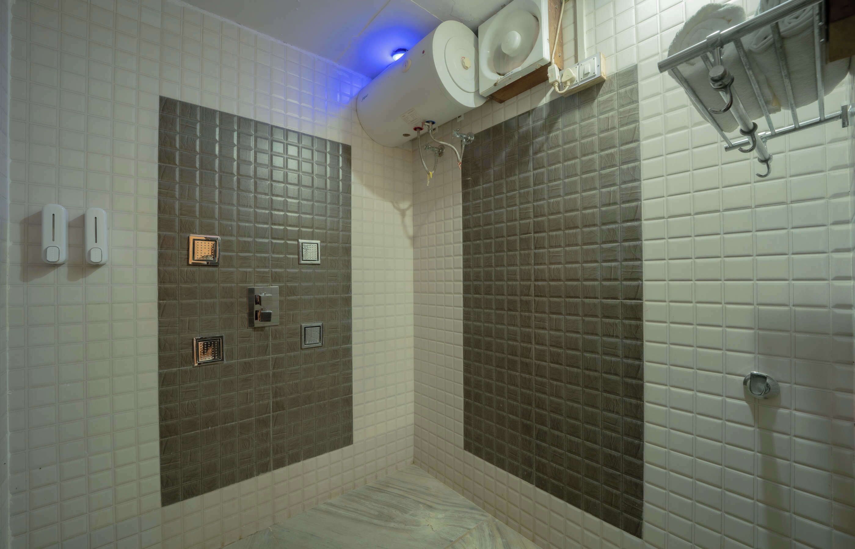 Une salle de bain avec des murs carrelés de blanc et de marron, un espace douche et des toilettes dotées d’un panneau de commande.