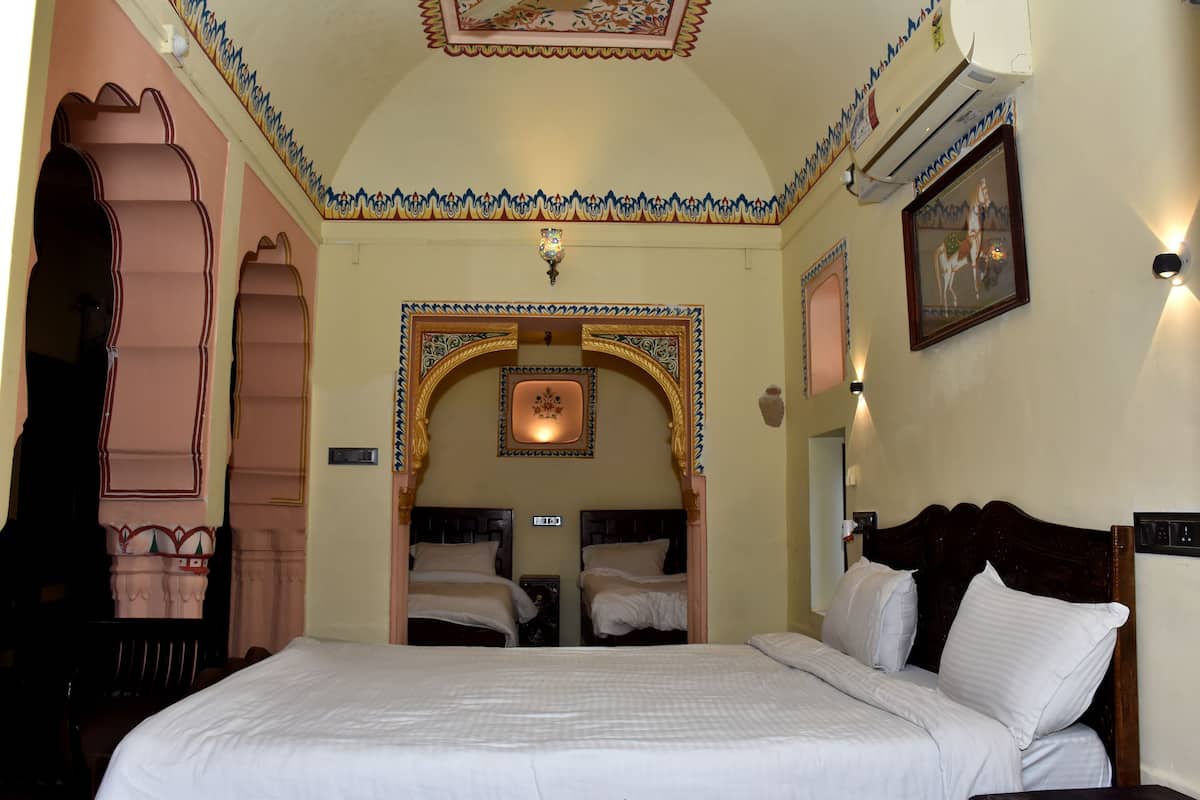 Een hotelkamer met een groot bed, twee nachtkastjes, een gewelfde deuropening en een decoratief plafond.