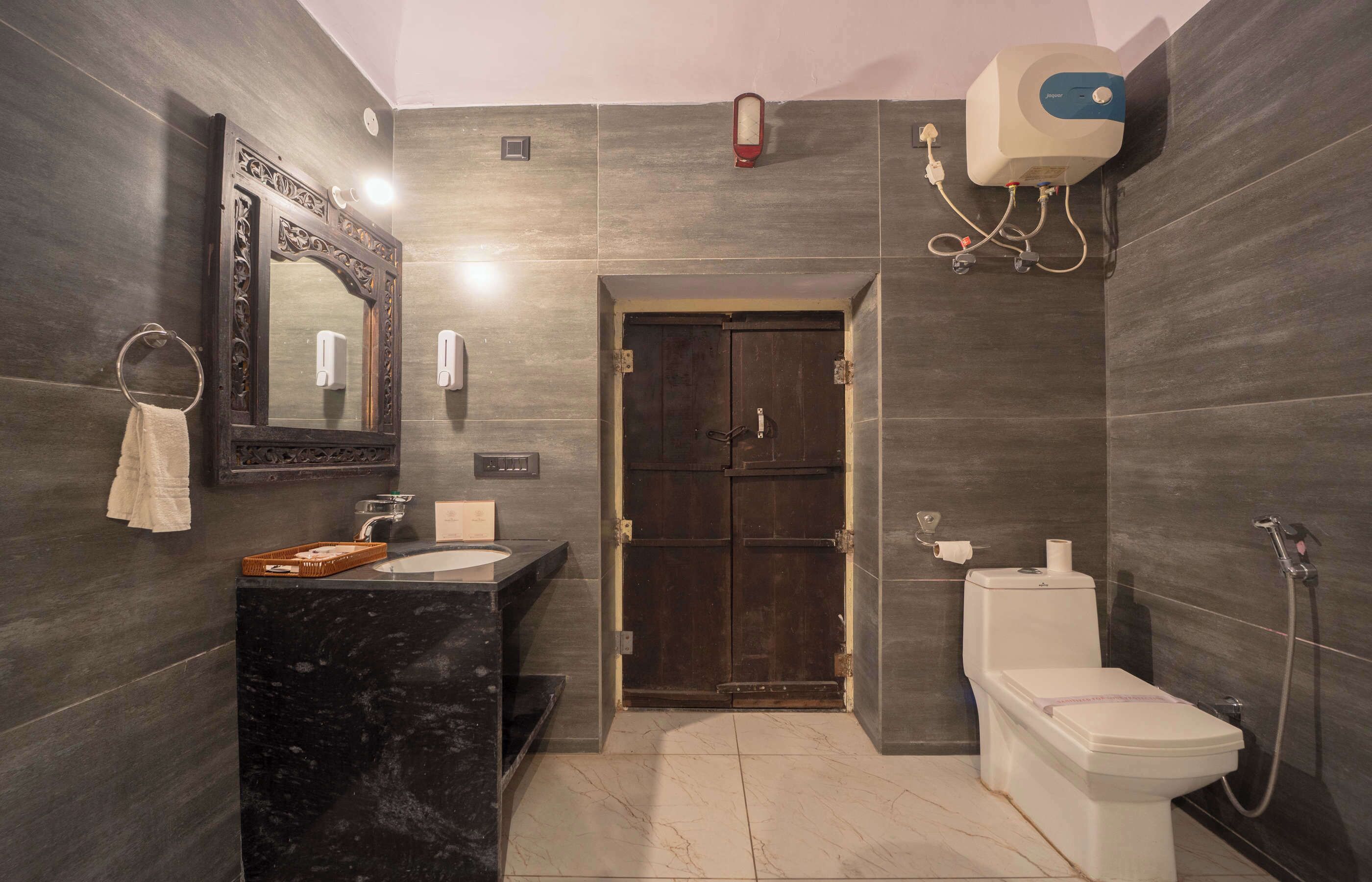 Un baño con lavamanos de mármol, inodoro, bidé y un espejo grande.