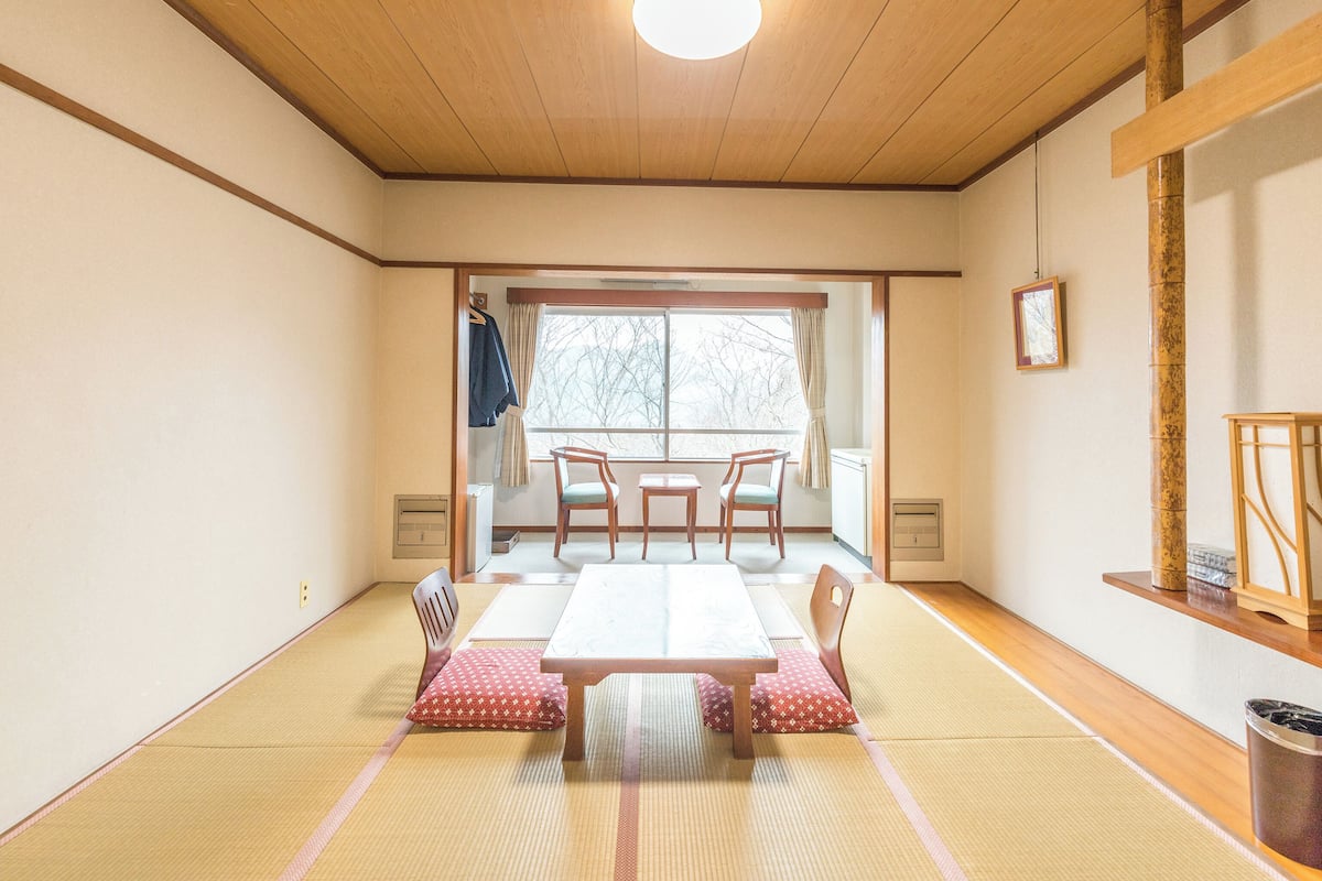 Una habitación japonesa tradicional con suelo de tatami, una mesa baja y sillas.