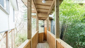 Una terraza de madera con piso y barandas, rodeada de follaje.
