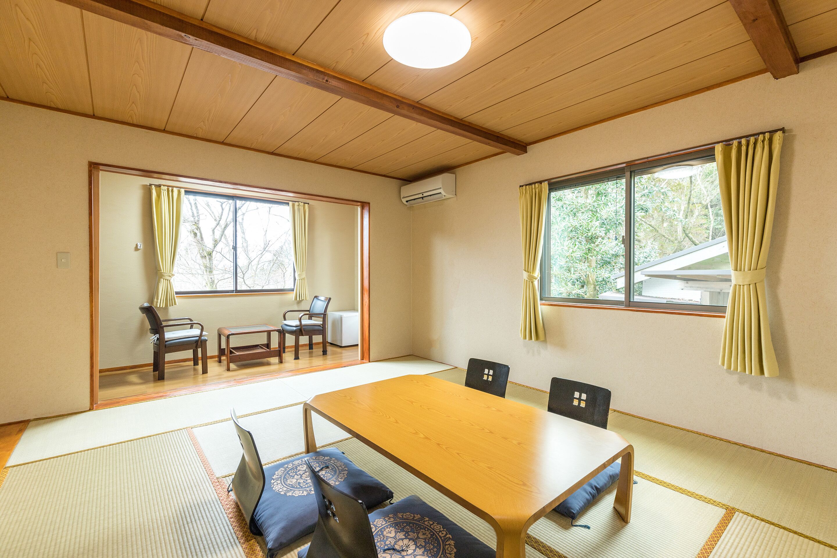 Una habitación japonesa tradicional con suelo de tatami, una mesa de madera y una puerta corredera que da a otra habitación.