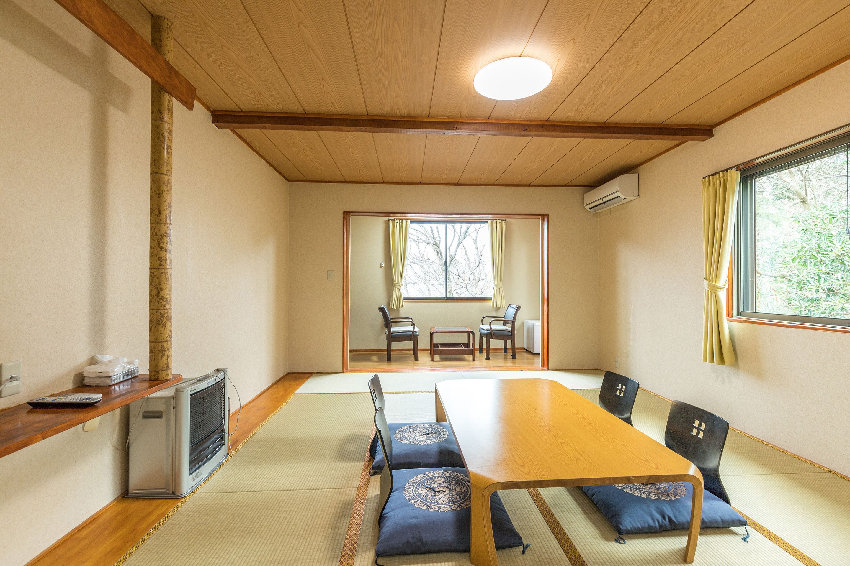 A traditional Japanese room with tatami flooring, a wooden table, and chairs.