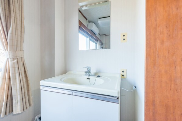 A bathroom with a white sink, a mirror, and a window with curtains.