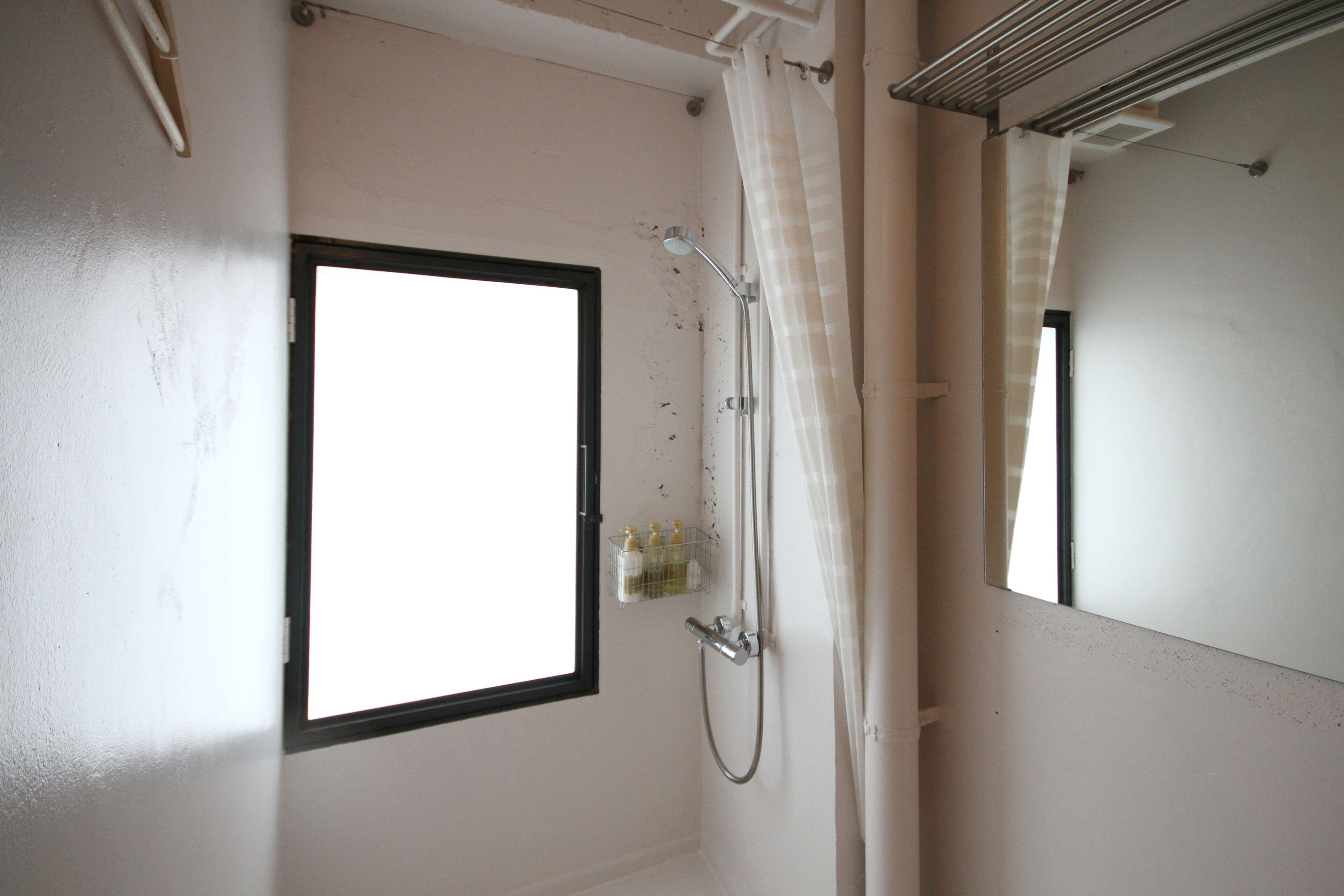 Ein Badezimmer mit Fenster, Dusche und Spiegel.