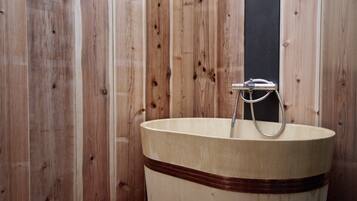 Una cabaña de madera con una bañera grande de madera y un grifo.