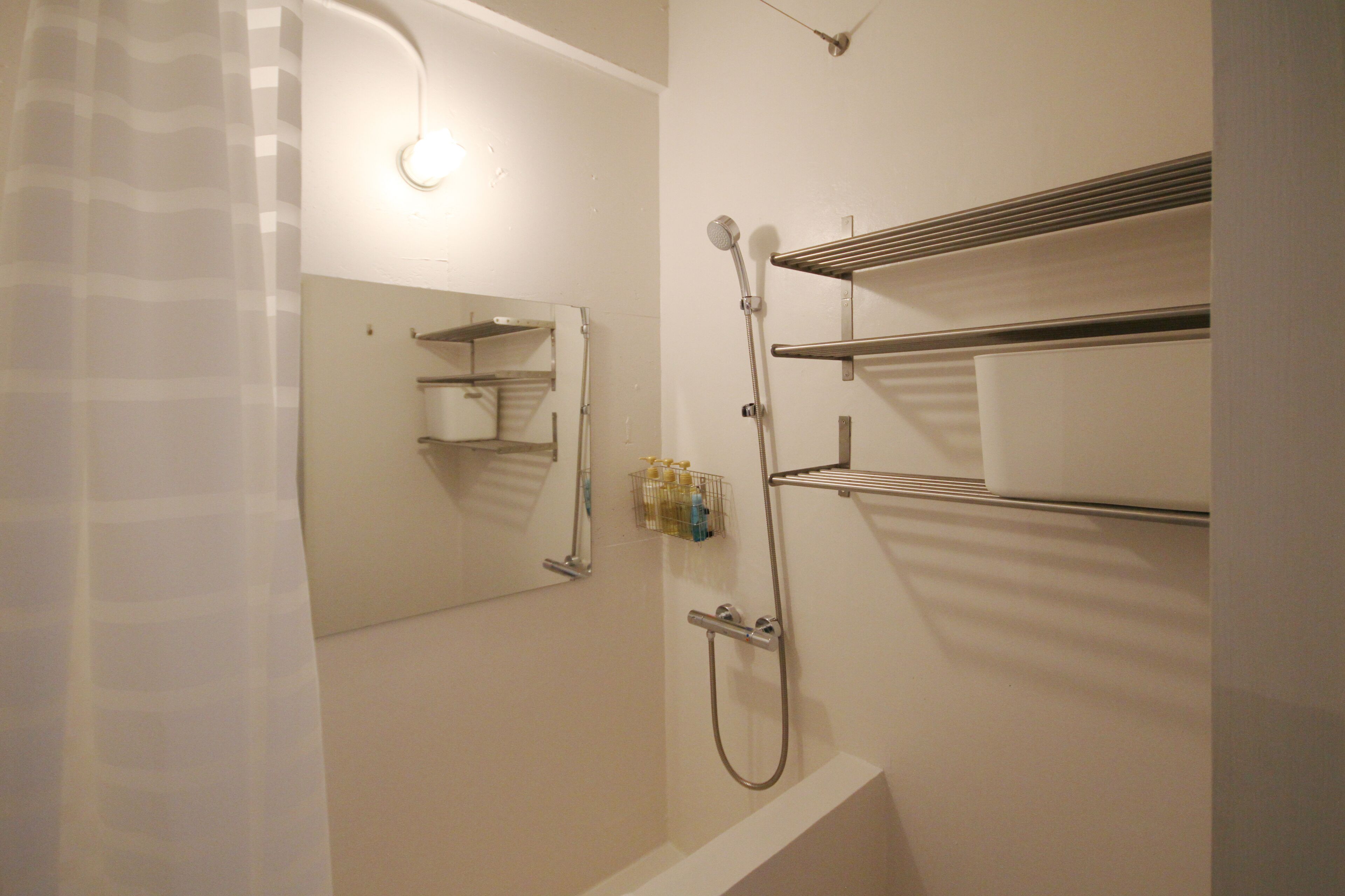 Ein Badezimmer mit Dusche, Spiegel und Ablageflächen für Pflegeprodukte.