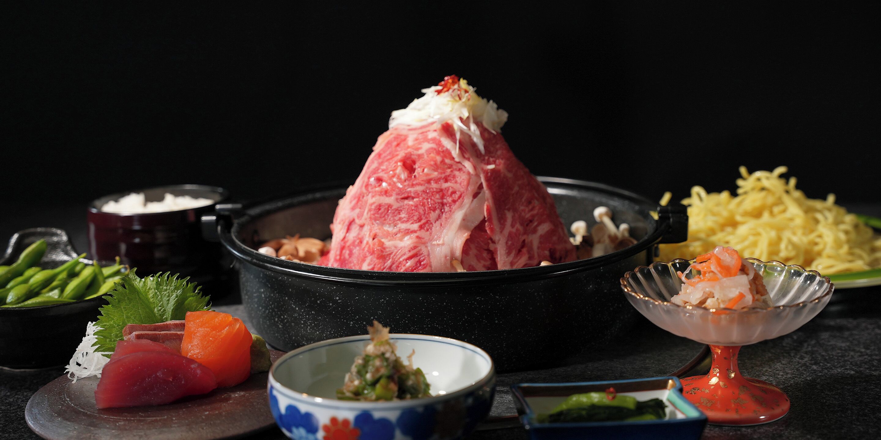 A traditional Japanese meal with various dishes including a bowl of soup, a plate of noodles, and a dish with seafood.
