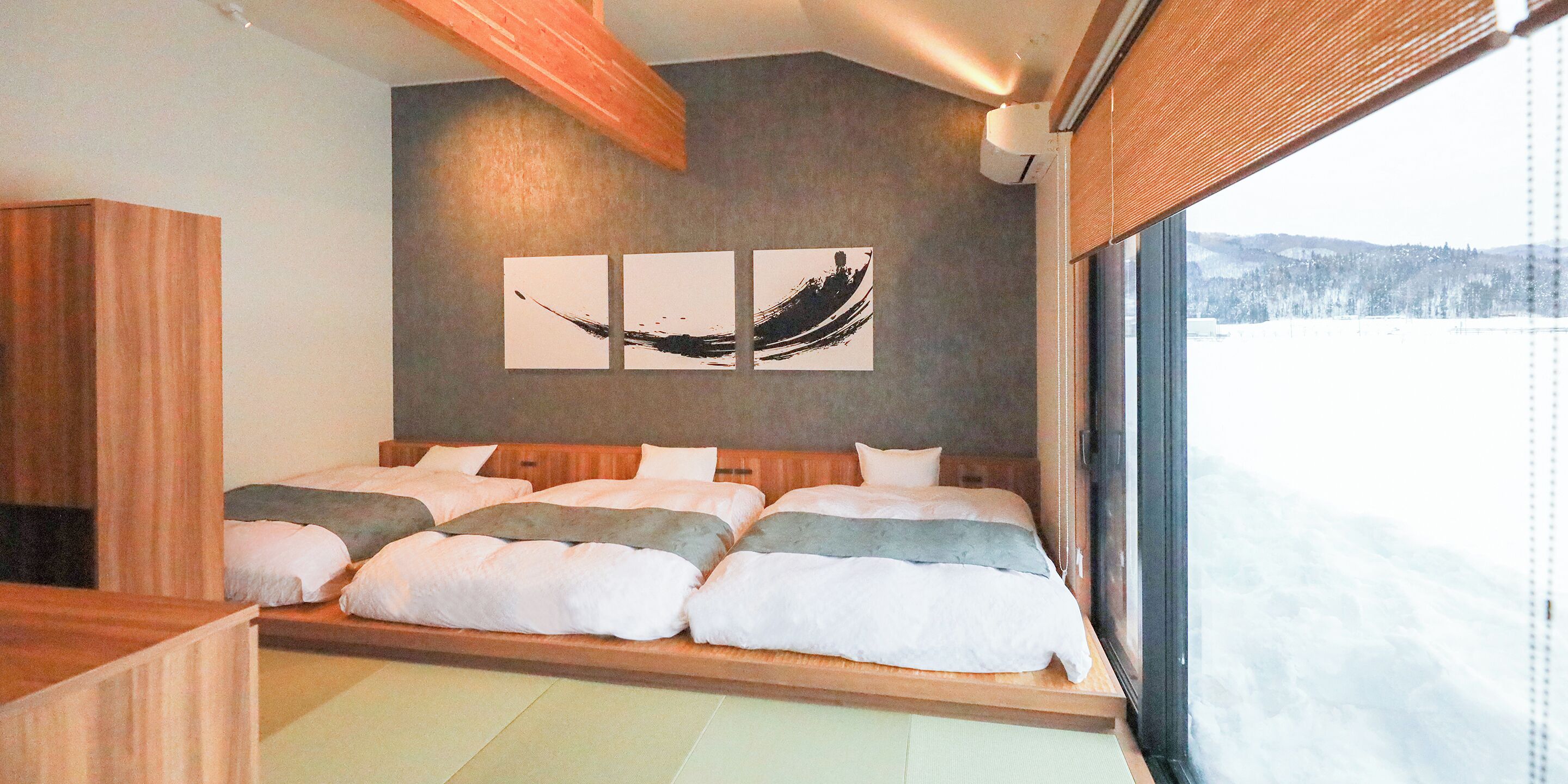 Un dormitorio moderno con una cama grande, cabecero de madera y vista a un paisaje nevado.