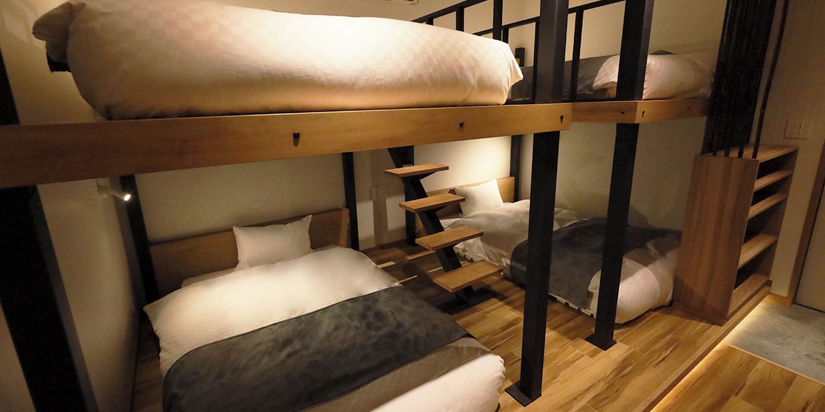 Ein Schlafraum mit Etagenbetten, Holzrahmen, einer Treppe und einer kleinen Sitzecke.