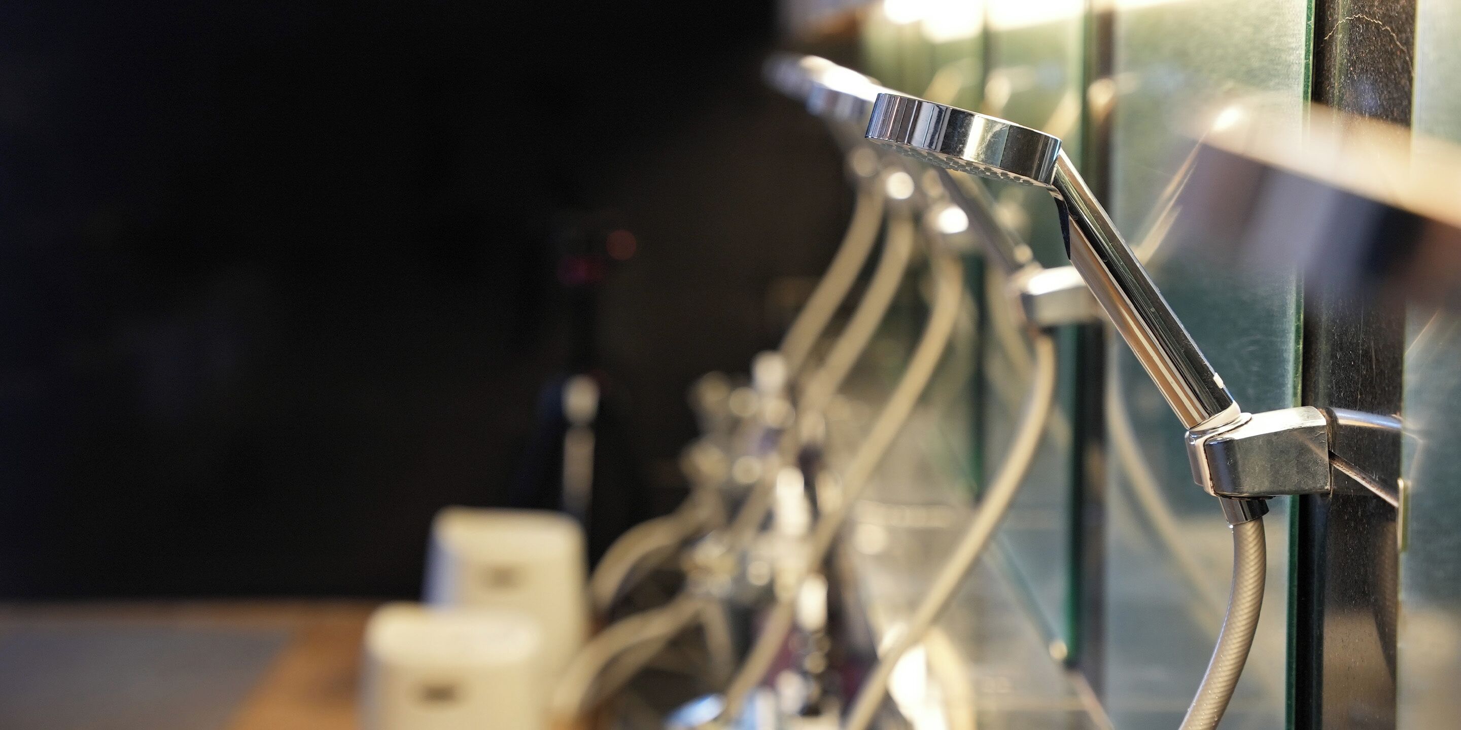A close-up of a metallic shower head with a flexible hose, part of a bathroom fixture.