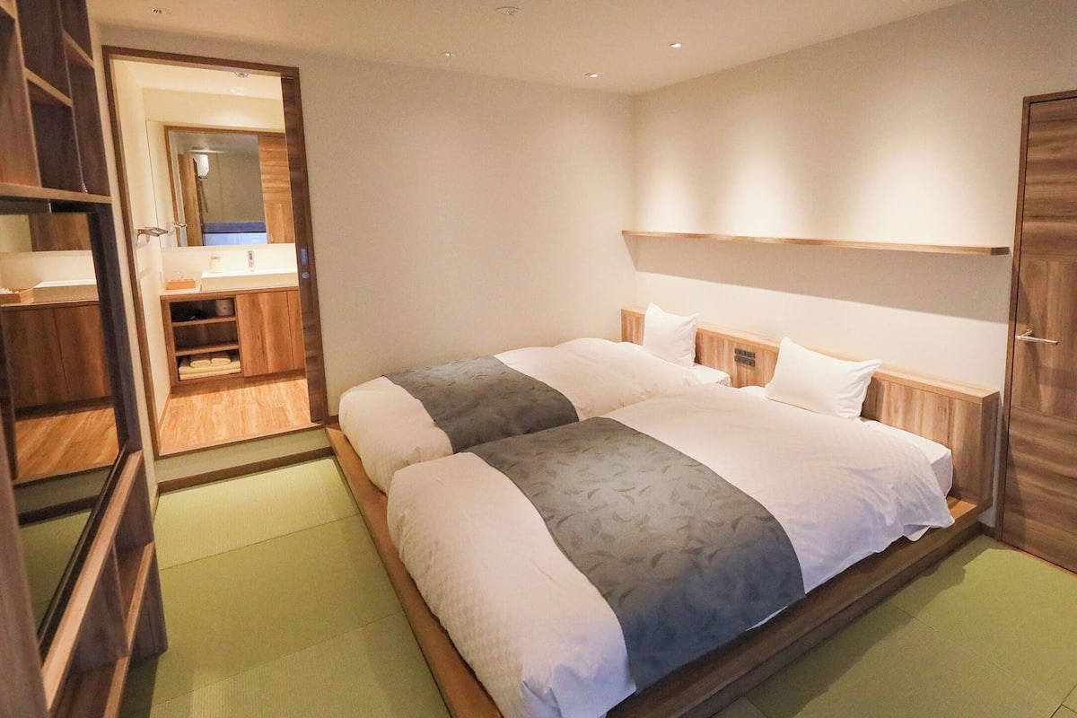 A hotel room with a bed, wooden wardrobe, and a bathroom visible through an open door.