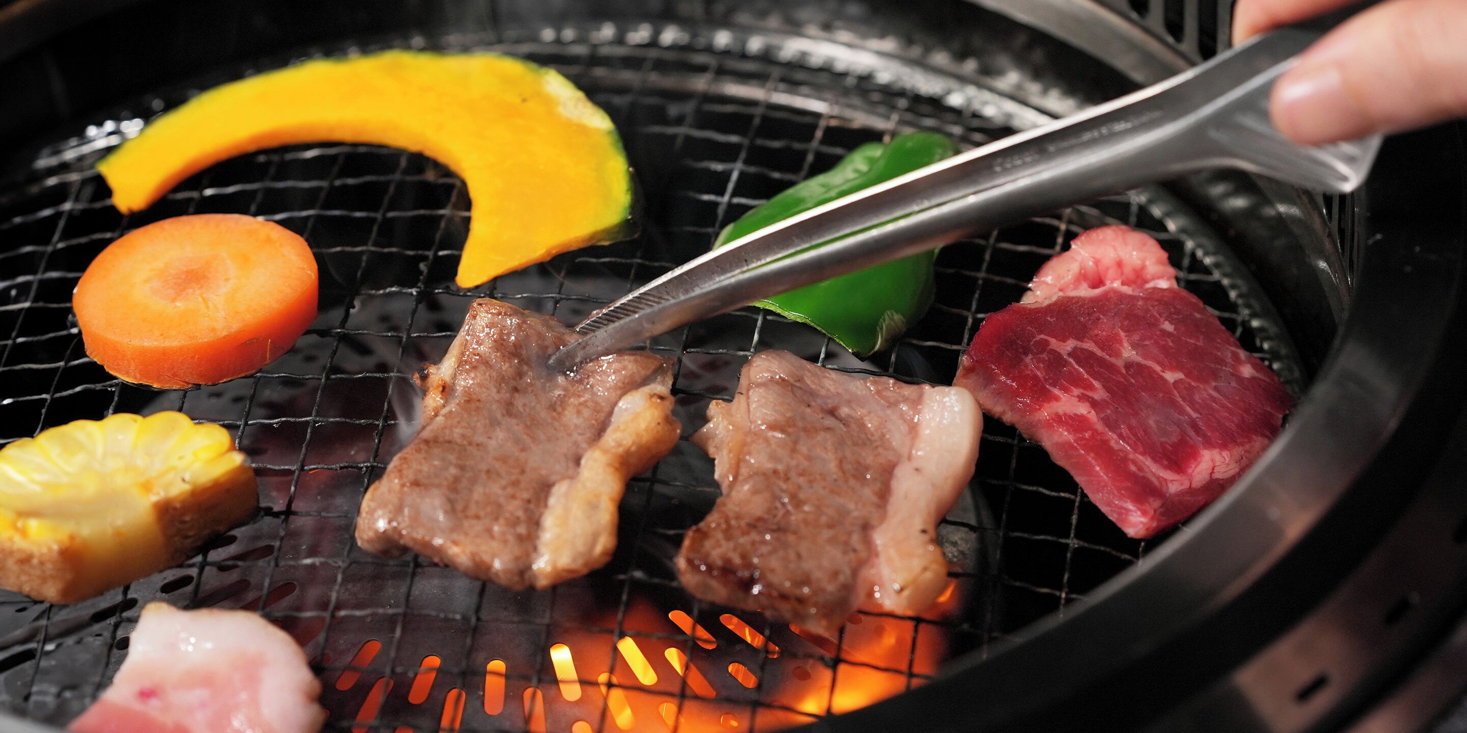 A grill with various meats and vegetables being cooked.