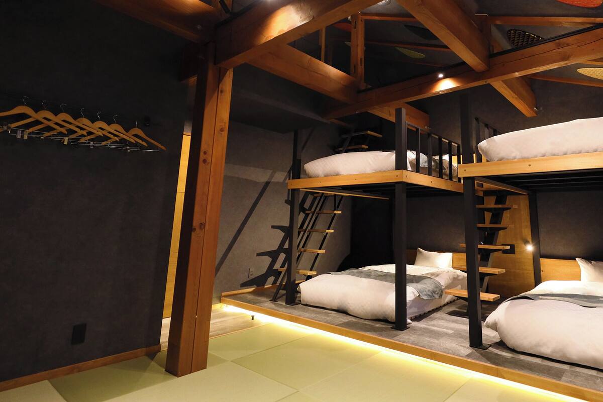 A bunk bed room with wooden beams, a ladder, and a window.